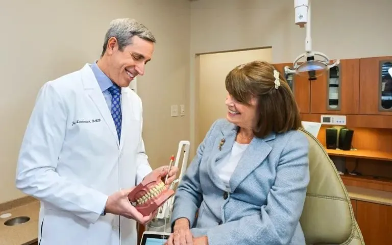 Laudenbach Periodontics dentist showing dental model to patient in treatment room