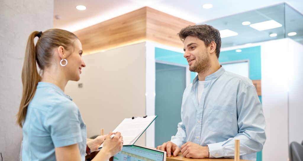 Man talking to professional receptionist in clinic
