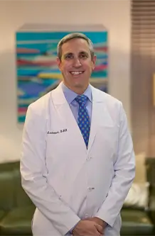 Laudenbach Periodontics dentist in white coat with blue tie, office portrait