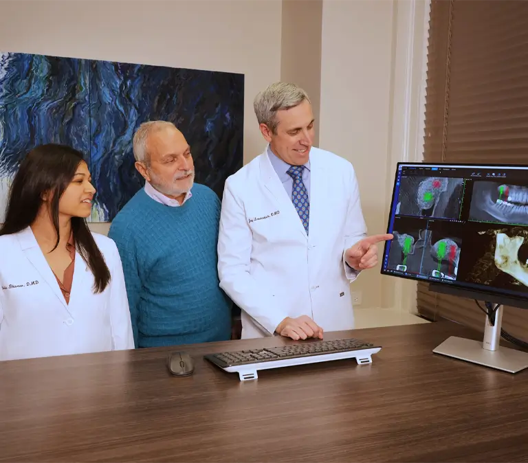Laudenbach Periodontics team reviews CT scan imaging with patient and colleague