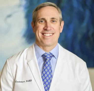 Laudenbach, DMD dental professional in white coat with blue patterned tie