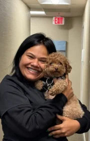 Laudenbach Periodontics & Dental Implants team member holding small brown dog in office hallway