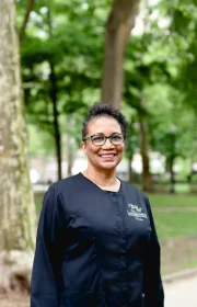 Laudenbach Periodontics & Dental Implants team member Chris smiling outdoors in black scrubs